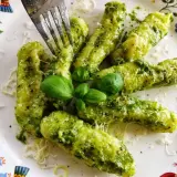 Pyszne domowe gnocchi z pesto, posypane parmezanem i udekorowane listkami bazylii. Idealne danie dla miłośników włoskich smaków.