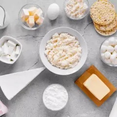 Różnorodne produkty bogate w wapń: mleko, sery, jogurt, masło, jajko i wafle ryżowe.