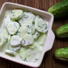 Mizeria na słodko z koperkiem w kremowym sosie, obok świeże ogórki. Idealna na letni obiad.