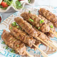 Pyszne, grillowane ćevapi na patyczkach, podane z sosem i sałatką. Idealne na letnie spotkania.