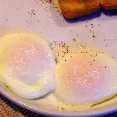 Dwa jajka sadzone na talerzu, posypane pieprzem. Szybki sposób, jak zrobic jajka w mikrofali.