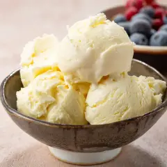Pyszne lody waniliowe, idealne na lato. Ten przepis na lody z maszynki jest prosty i szybki. W tle miseczka z borówkami i malinami.