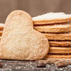 Stos cukrowych ciastek w kształcie serca i okrągłych, idealnych na prosty przepis na ciastka. Obok ziarna kawy i sznurek.