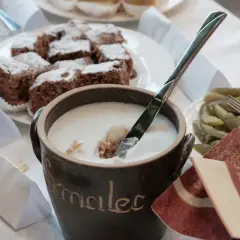 Gęsty smalec w glinianym naczyniu, obok ciasto czekoladowe i ogórki.