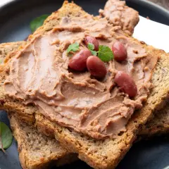 Pyszna pasta z czerwonej fasoli na chrupiących tostach, udekorowana fasolkami i listkami ziół. Idealna na śniadanie.