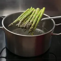 Zielone szparagi gotują się w garnku. Wkrótce dowiesz się, jak smakują szparagi.