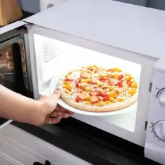 Ręka wkłada mrożoną pizzę do mikrofali. Czy mrożona pizza nadaje się do mikrofali? Zobaczmy!