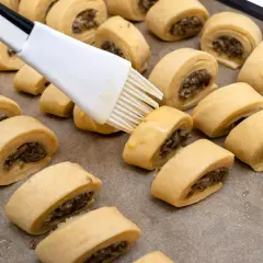 Paszteciki z farszem grzybowym na blasze, smarowane pędzlem jajkiem.