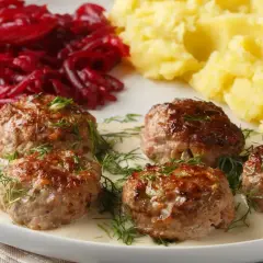 Pięć soczystych klopsów w kremowym sosie, udekorowanych koperkiem, podanych z purée ziemniaczanym i buraczkami.