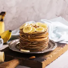 Stos naleśników z plasterkami banana i orzechami. Idealny pomysł, co zrobić z bananów na pyszne śniadanie.