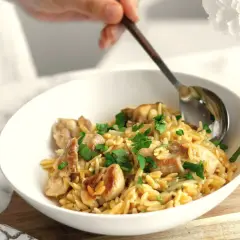 Miseczka z kurczakiem i makaronem orzo, posypana natką pietruszki. Idealne na proste przepisy na obiad.