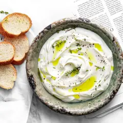 Labneh co to? Kremowy, gęsty serek z jogurtu, polany oliwą i posypany ziołami, podany z chrupiącym pieczywem.