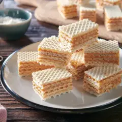 Słodkie kwadraty z kruchej masy do wafli, przełożone kremowym karmelem, kuszą swoim wyglądem.