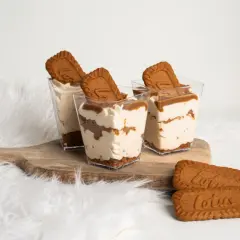 Trzy deserki w pucharkach z kremem i pokruszonymi ciastkami Lotus, ozdobione ciasteczkami Lotus.