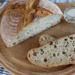 Pyszny chleb pszenno żytni na zakwasie, pokrojony na desce, z solniczką i nożem w tle. Idealny na śniadanie.