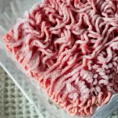 Mrożone mięso mielone w plastikowym opakowaniu, gotowe do rozmrożenia w mikrofali.