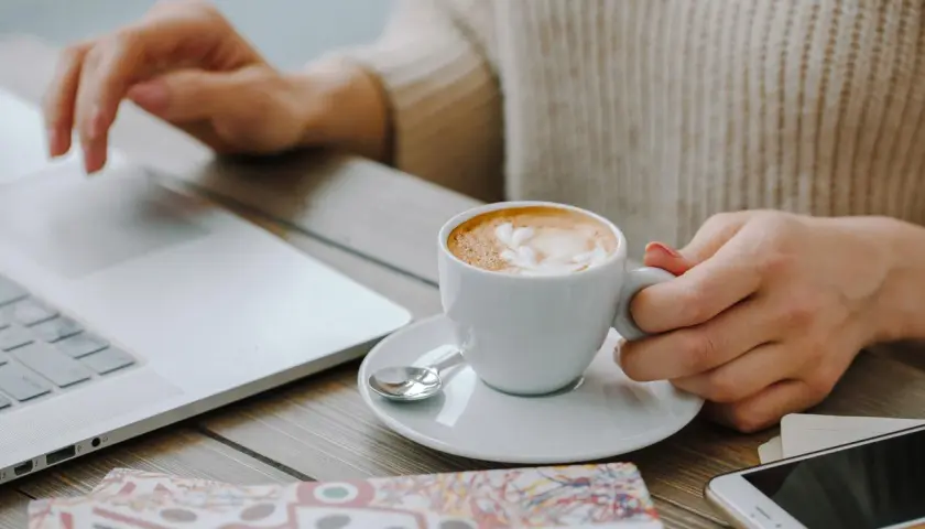 Kawa Davidoff rozpuszczalna, która najlepsza? Pyszne latte z pianką obok laptopa i telefonu.