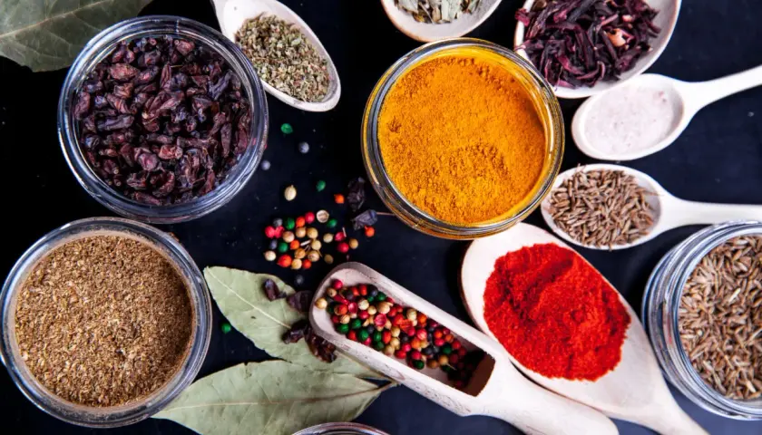 Kolorowe przyprawy, w tym kurkuma, papryka i kmin rzymski, ułożone na czarnym tle. Idealne do przygotowania aromatycznego garam masala przepis.
