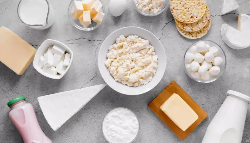 Różnorodne produkty bogate w wapń: mleko, sery, jogurt, masło, jajko i wafle ryżowe.