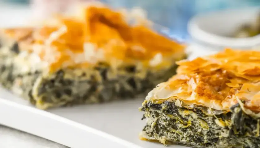 Chrupiąca spanakopita z warstw ciasta filo i zielonym nadzieniem ze szpinaku i sera.