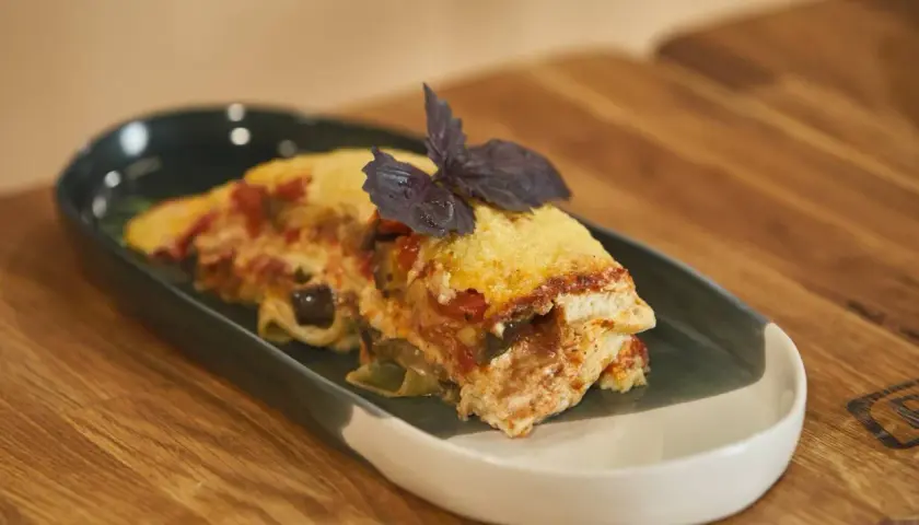 Pyszna lasagne z bakłażanem i pomidorami, udekorowana bazylią. Idealna, gdy zastanawiasz się, jak podgrzać lasagne w mikrofali.