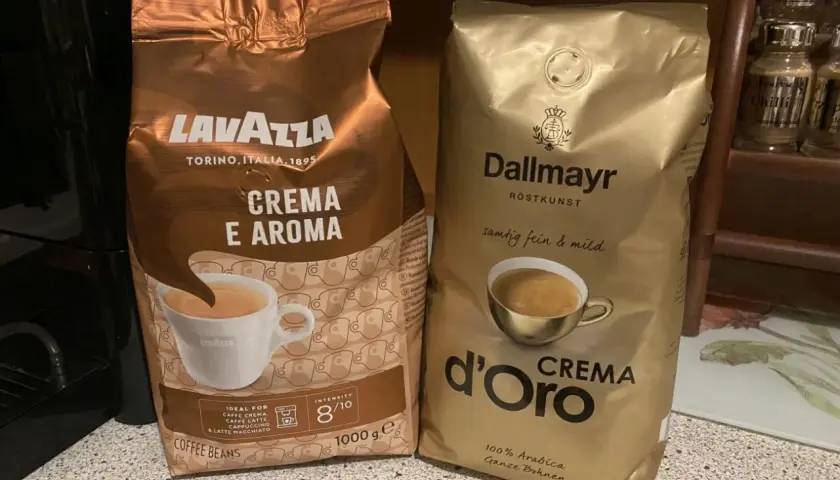 Dwie paczki kawy ziarnistej: Lavazza Crema e Aroma i Dallmayr d'Oro Crema. Idealne do przygotowania pysznego espresso, stanowią podstawę rankingu kaw ziarnistych.