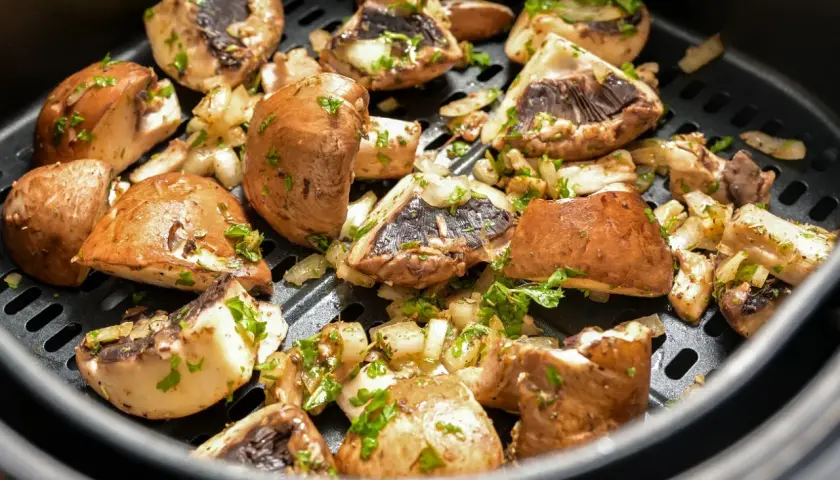 Pyszne pieczarki z airfryer, przyprawione i posypane natką pietruszki, gotowe do podania.