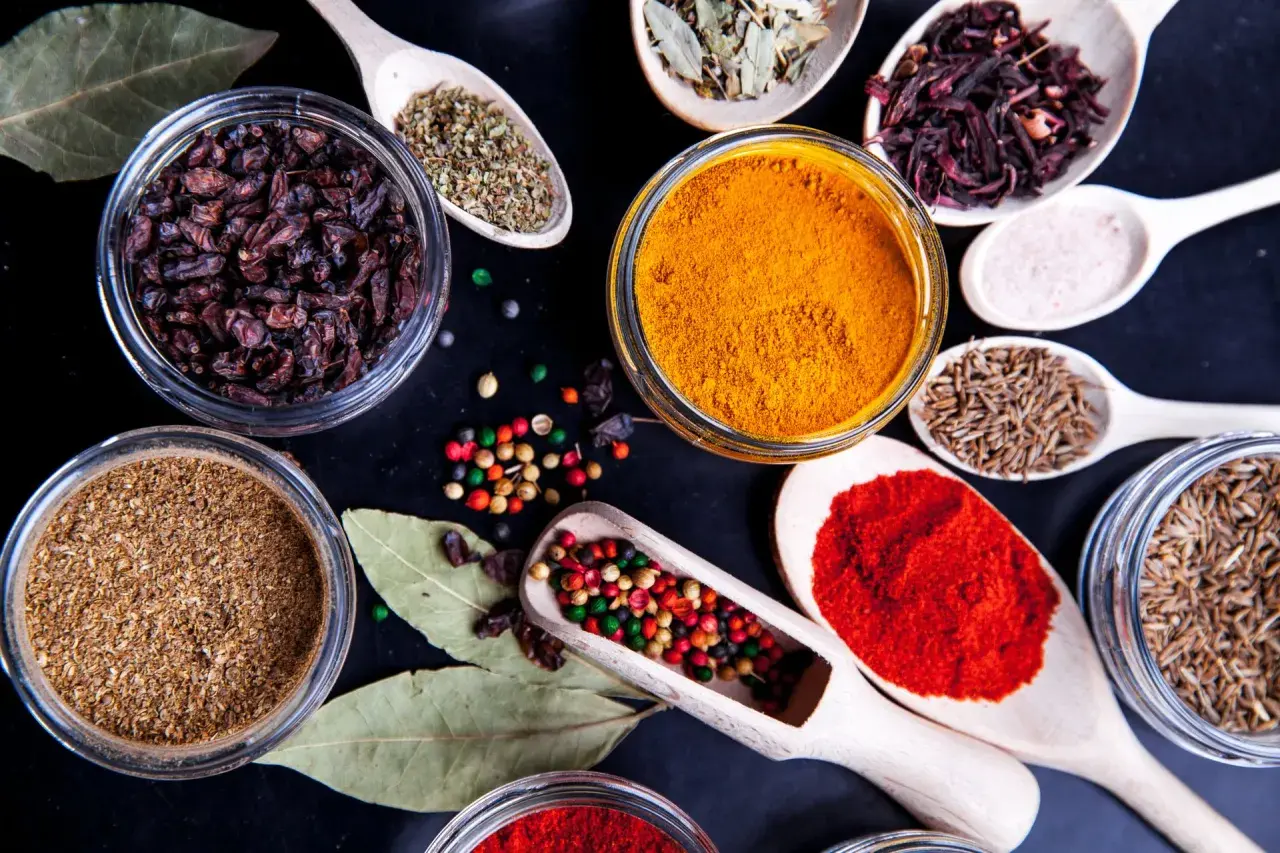 Kolorowe przyprawy, w tym kurkuma, papryka i kmin rzymski, ułożone na czarnym tle. Idealne do przygotowania aromatycznego garam masala przepis.
