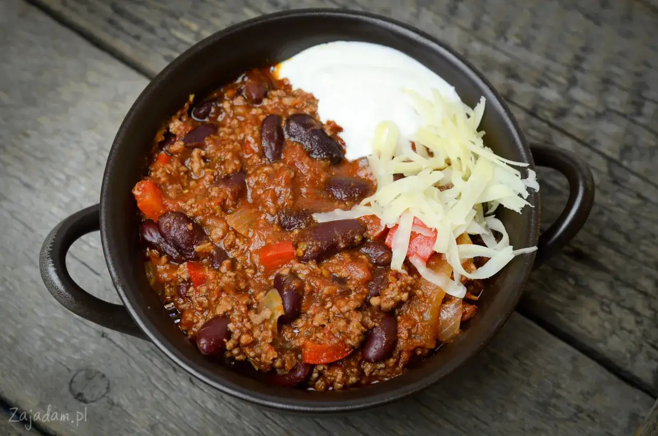 Chili con carne przepis oryginalny: sycące danie z mielonym mięsem, fasolą i warzywami, podane z kleksem śmietany i startym serem.