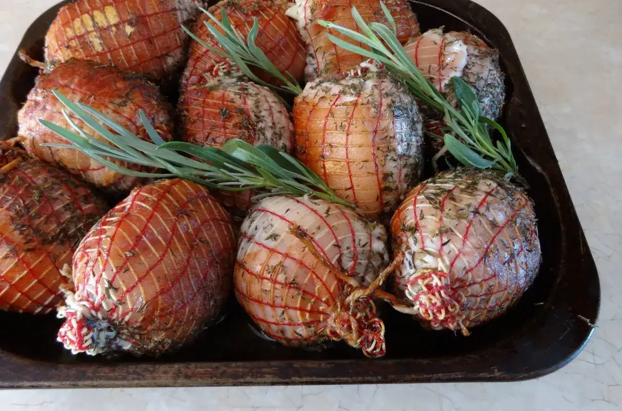 Gotowe do pieczenia golonki w siatce, przyprawione ziołami. Czas pieczenia zależy od wielkości, ale warto wiedzieć, jak długo gotować golonkę w siatce.