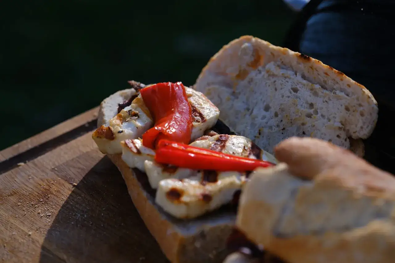 Pyszny sandwich z chrupiącym pieczywem, grillowanym halloumi i papryką, gotowy do zjedzenia na świeżym powietrzu.