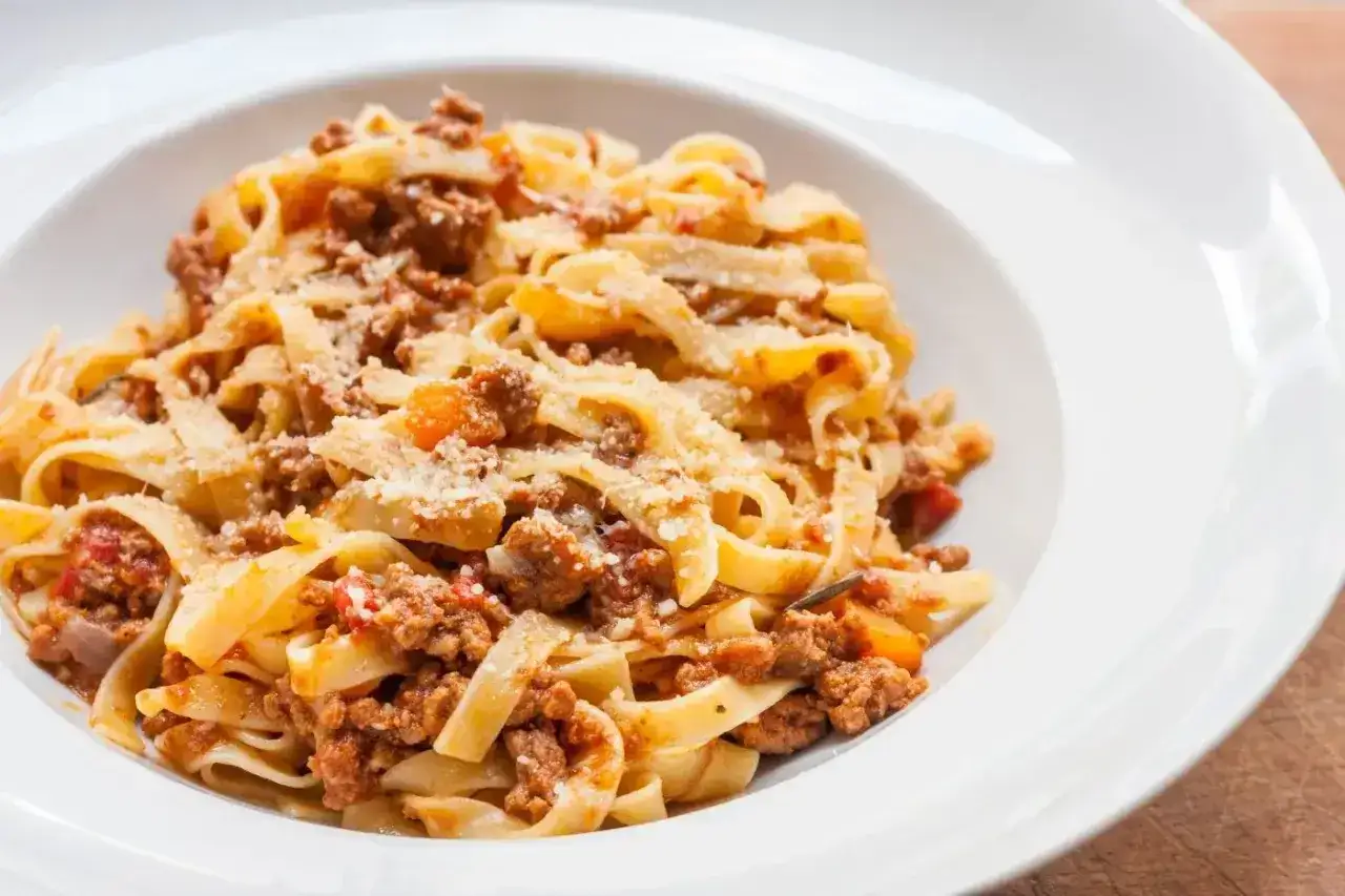 Tagliatelle z bogatym sosem mięsnym ragu, posypane parmezanem. Idealny przepis na obiad.