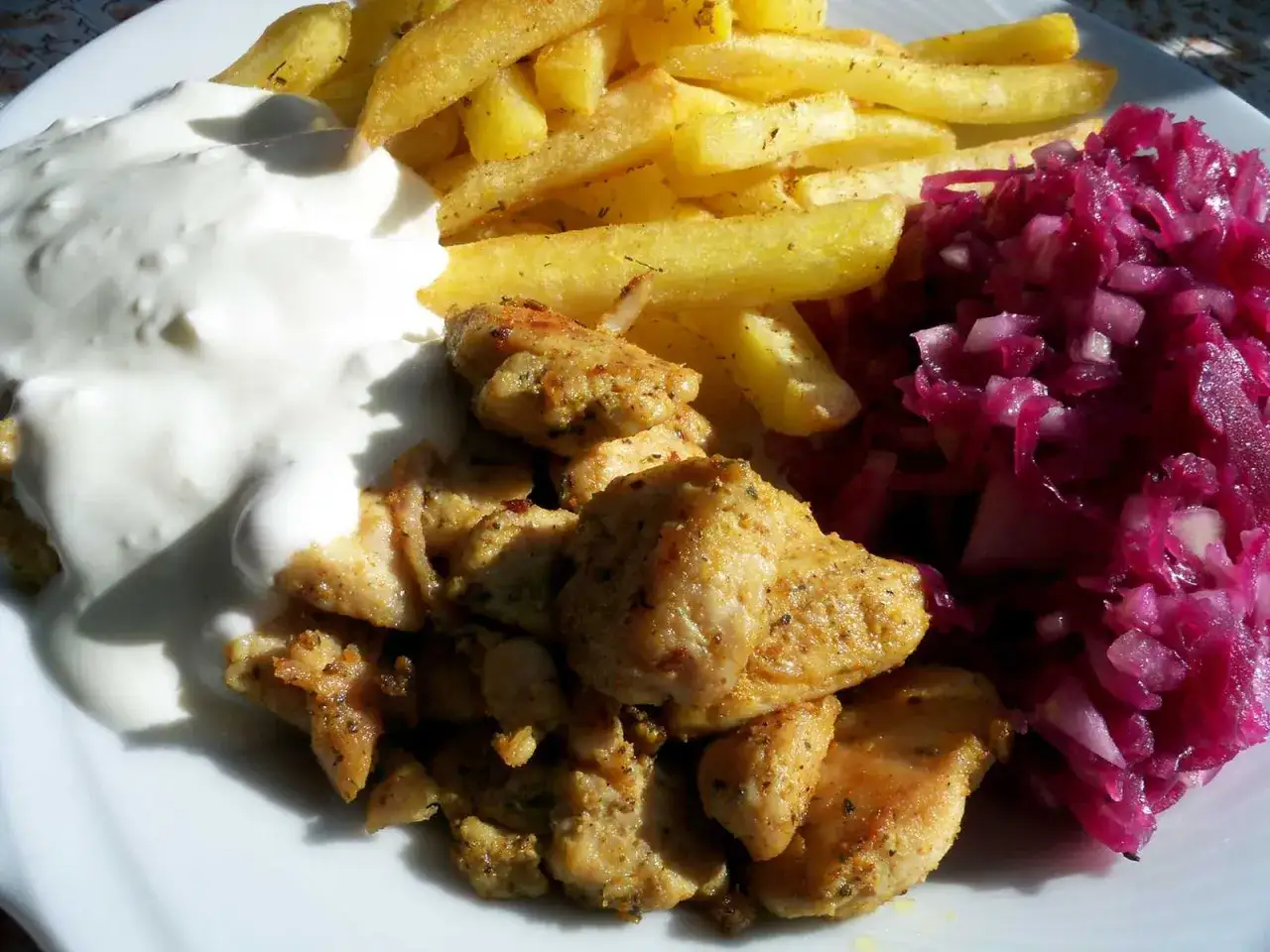 Pyszna shoarma z kurczaka z frytkami, sosem czosnkowym i czerwoną kapustą.