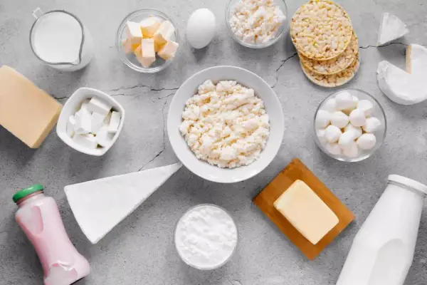 Różnorodne produkty bogate w wapń: mleko, sery, jogurt, masło, jajko i wafle ryżowe.