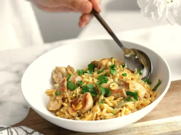 Miseczka z kurczakiem i makaronem orzo, posypana natką pietruszki. Idealne na proste przepisy na obiad.